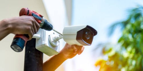A Wireless CCTV camera setting outside building with white box water poof with sun blur background.